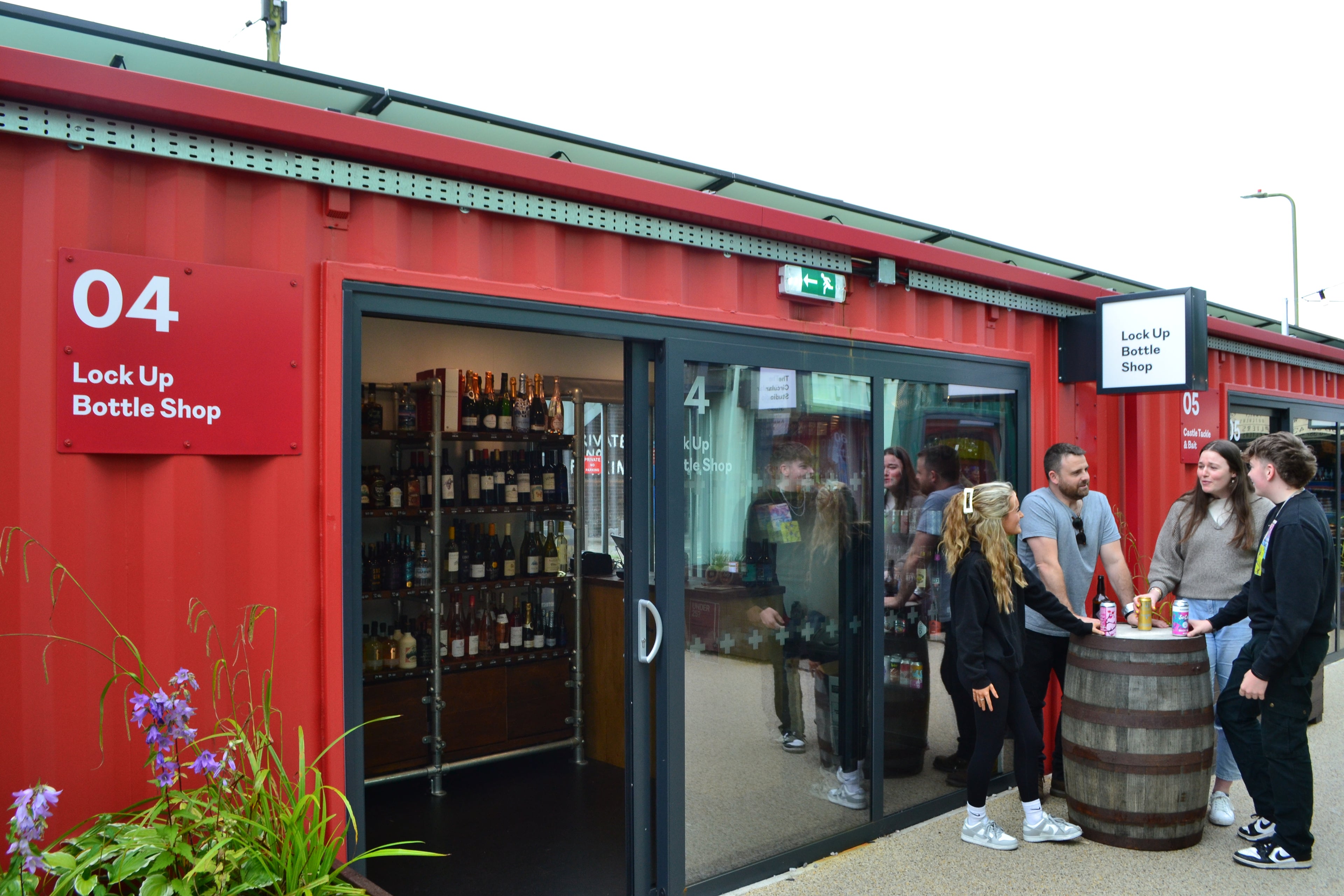 A picture of the front of Lockup Bottle Shop with people outside drinking craft beer and cider